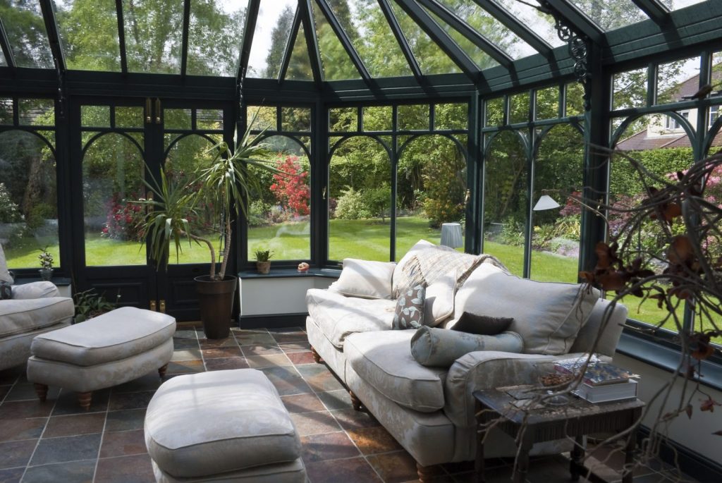 Green orangery with cream sofa and tiled floor
