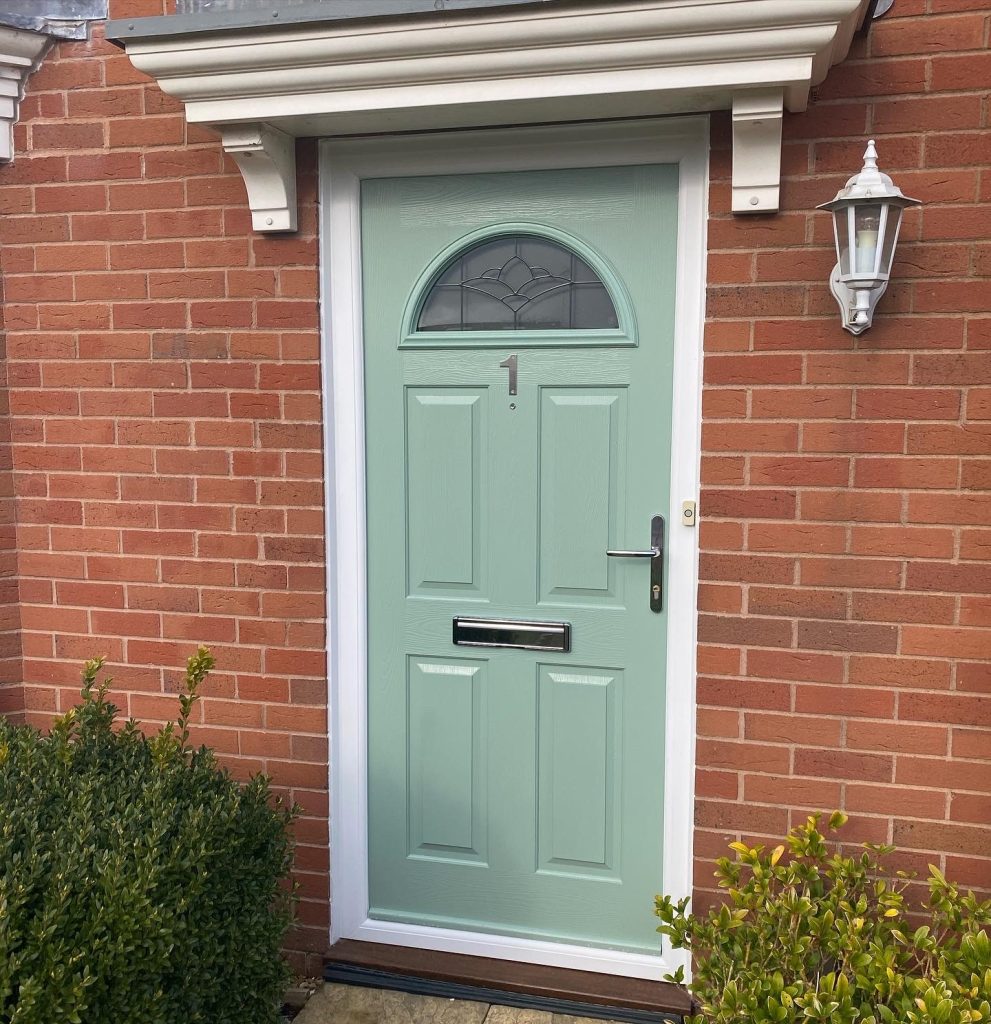 Light green classic looking front door with half moon window.