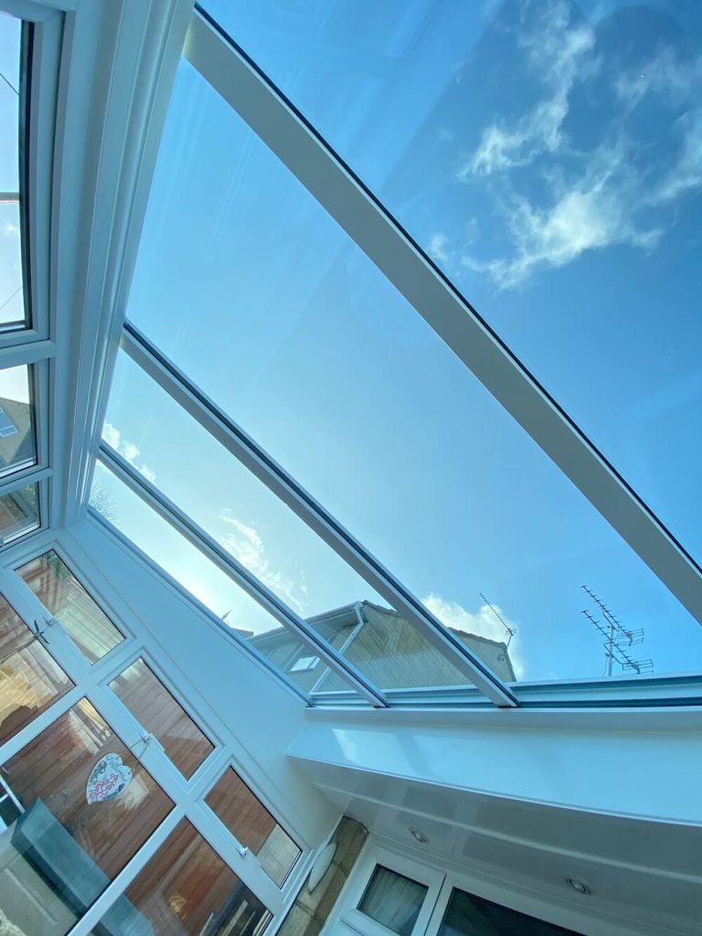A close up of a conservatory glass roof with blue sky views