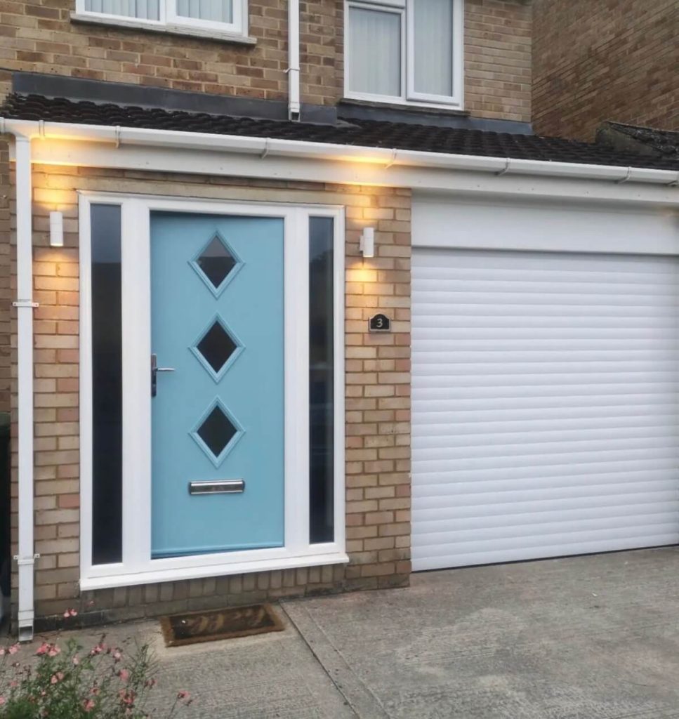 Light blue composite front door with diamond windows, set in a modern brick house with white frame, side panels, and a garage door.
