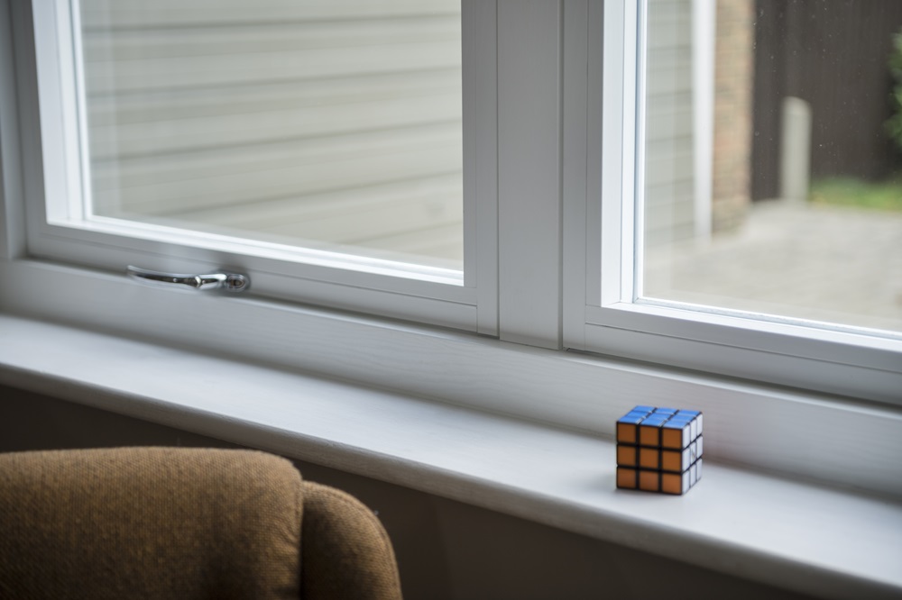 Serene view from a window with a Rubik's cube on the sill, framed by timber effect windows.