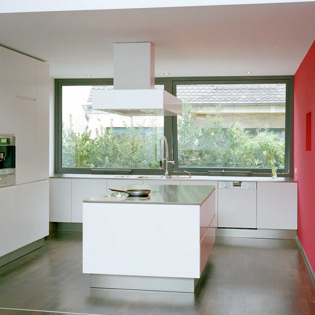 Aluminium windows in a modern kitchen with a view of bushes.