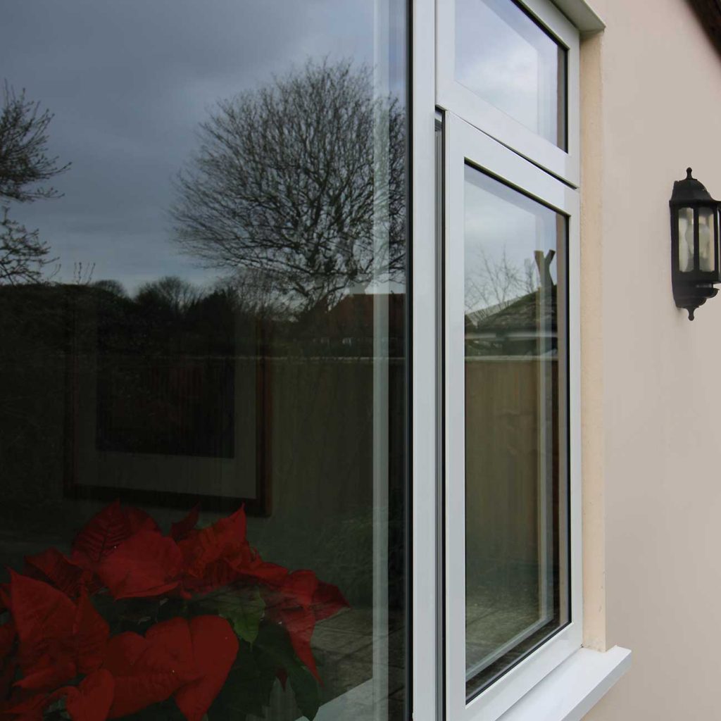 An aluminium window with the reflection of a tree in it.