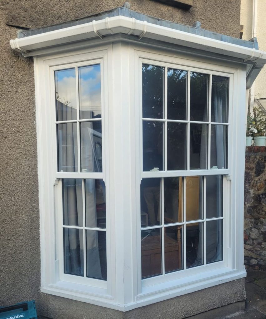 White uPVC bay window with Georgian bars on a rendered house exterior.